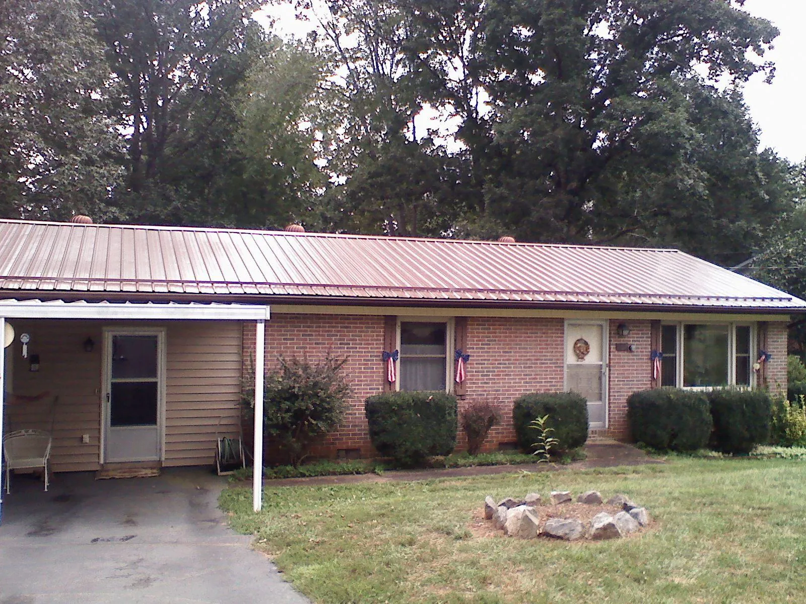 Bronze metal roof and carport on a brick ranch home — Roof Repair work by our crew in Stewart