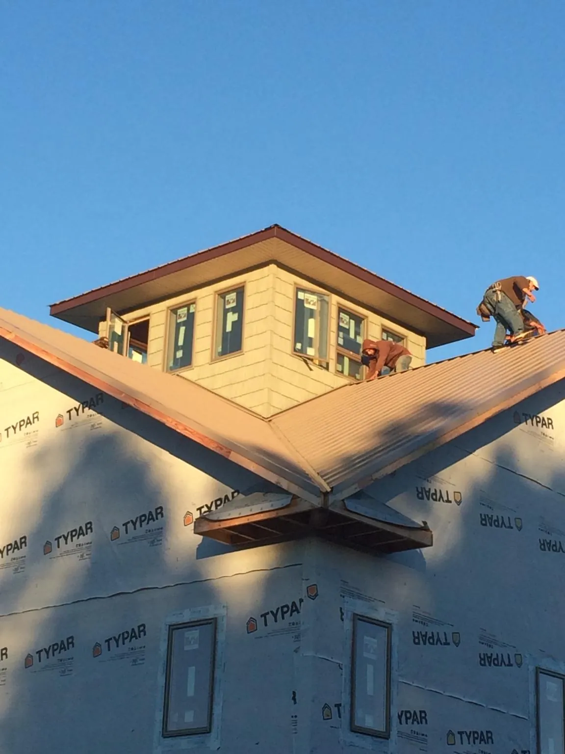 Roofers working around a rooftop cupola on a new metal roof at sunset — Roof Waterproofing in Stewart by Roofing Brothers